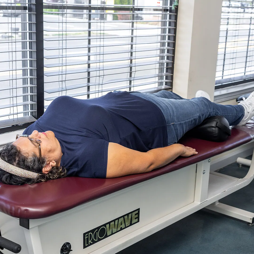 Woman lying in a spinal decompression table in clinic