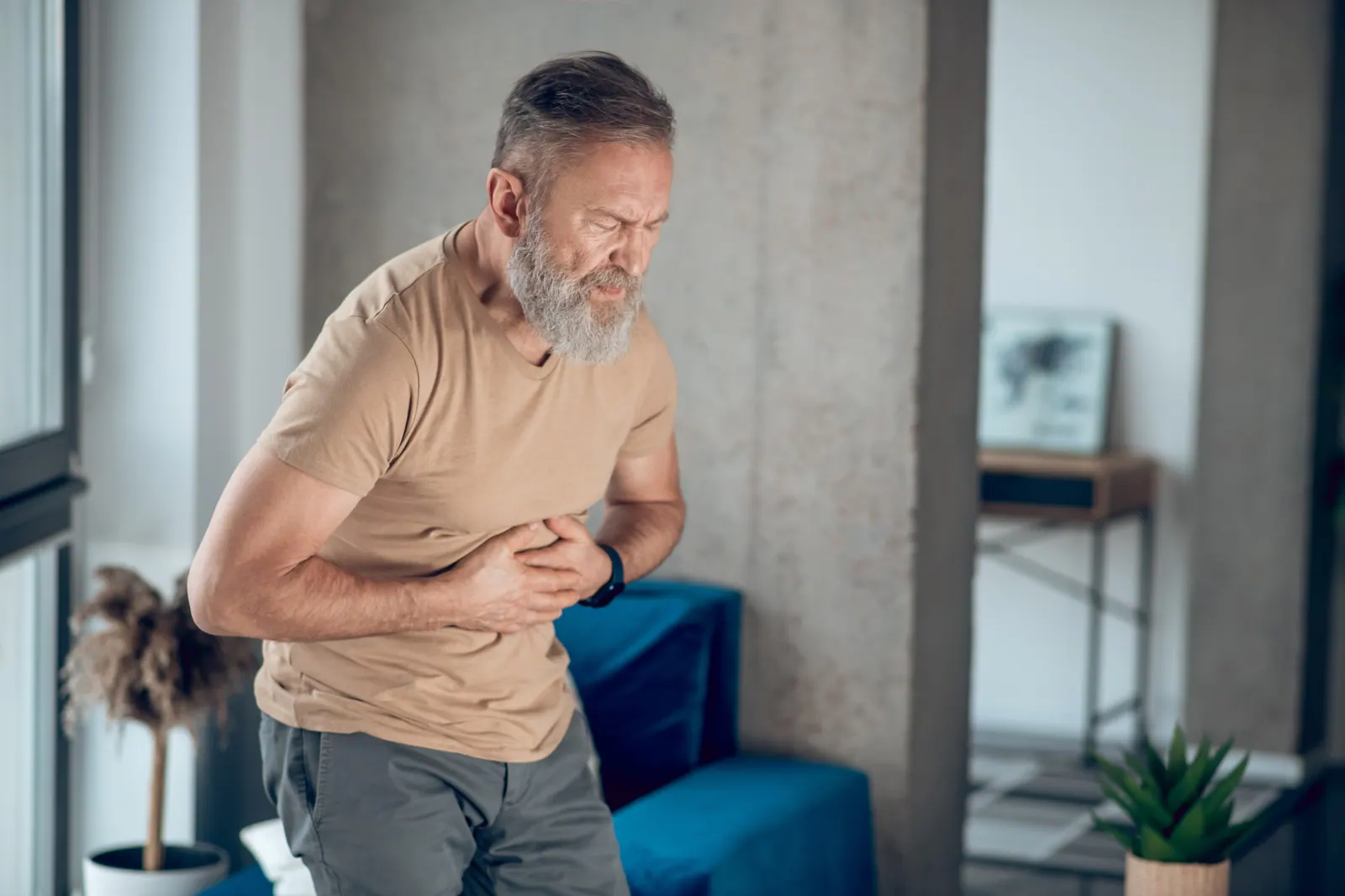 Older man bent over with stomach pain
